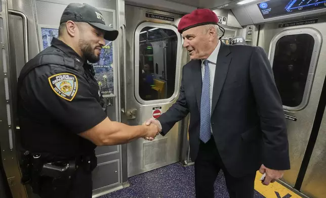 New York Mayor candidate Curtis Sliwa meets a New York City Police Department officer as he campaigns in the New York City subway system, Monday, Aug. 18, 2025. (AP Photo/Richard Drew)
