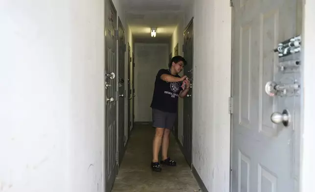 Liz Silva locks the door to a storage unit containing her friend Maria Pires' belongings in Baltimore, Wednesday, June 25, 2025. (AP Photo/Stephanie Scarbrough)
