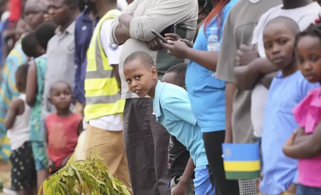 A boy peers out from the crowd to watch the riders competing in the men's Under 23 individual time trial event, at the road cycling World Championships in Kigali, Rwanda, Monday, Sept. 22, 2025. (AP Photo/Jerome Delay)