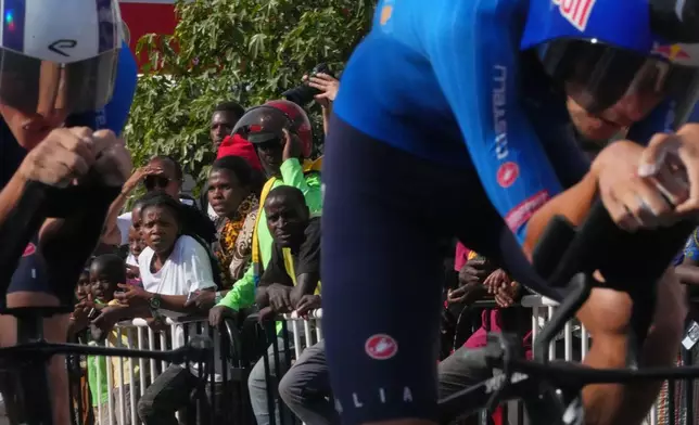 Spectators watch the Italian team riding past, during the team time trial mixed relay event, at the road cycling World Championships in Kigali, Rwanda, Wednesday, Sept. 24, 2025. (AP Photo/Jerome Delay)
