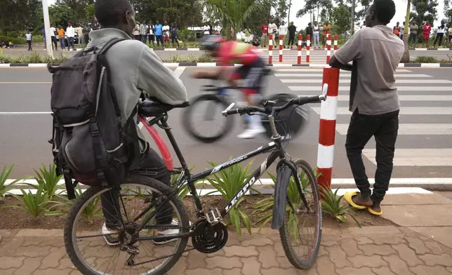 A rider speeds past spectators during the men's Under 23 individual time trial event, at the road cycling World Championships in Kigali, Rwanda, Monday, Sept. 22, 2025. (AP Photo/Jerome Delay)