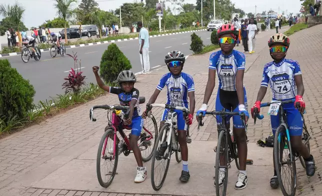 Boys on their bicycles stand by the track, during the team time trial mixed relay event, at the road cycling World Championships in Kigali, Rwanda, Wednesday, Sept. 24, 2025. (AP Photo/Jerome Delay)