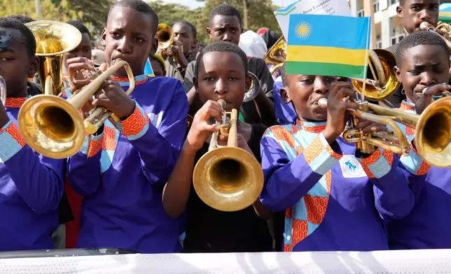 Boys play trumpets as the follow the men's Under 23 road race, at the road cycling World Championships in Kigali, Rwanda, Friday, Sept. 26, 2025. (AP Photo/Jerome Delay)