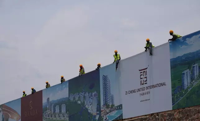 Workers watch the men's Under 23 road race, at the road cycling World Championships in Kigali, Rwanda, Friday, Sept. 26, 2025. (AP Photo/Jerome Delay)