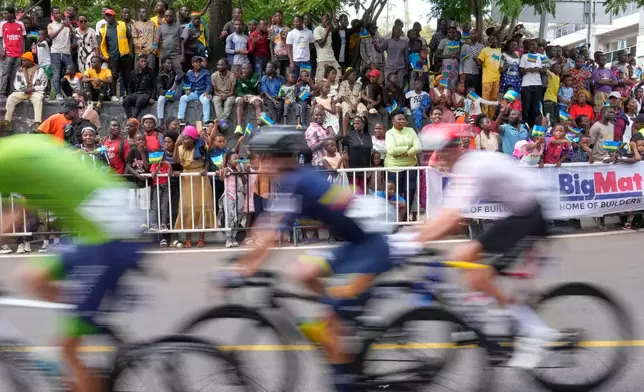 Riders pedal past spectators during the men's Under 23 road race, at the road cycling World Championships in Kigali, Rwanda, Friday, Sept. 26, 2025. (AP Photo/Jerome Delay)