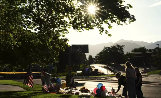 Women place flowers at a memorial outside Utah Valley University after Turning Point USA CEO and co-founder Charlie Kirk was shot and killed, Saturday, Sept. 13, 2025, in Orem, Utah. (AP Photo/Lindsey Wasson)
