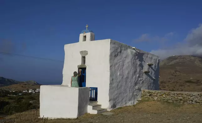 Bernadette Foskolos cleans her Agios Athanasios family-owned chapel at the village of Steni, on the island of Tinos, Greece, Saturday, Sept. 6, 2025. (AP Photo/Petros Giannakouris)