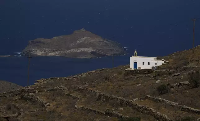 A family-owned chapel on the island of Tinos, Greece, with the isle of Planitis in the background, is seen on Saturday, Sept. 6, 2025. (AP Photo/Petros Giannakouris)