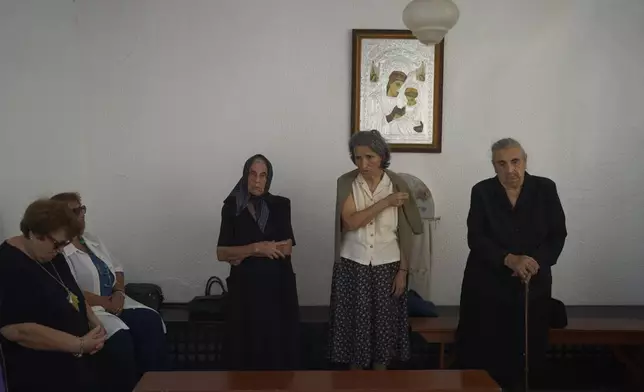 Worshippers make the Sign of the Cross during a liturgy at the family-owned Agios Sostis chapel on the island of Tinos, Greece, Monday, Sept. 8, 2025. (AP Photo/Petros Giannakouris)