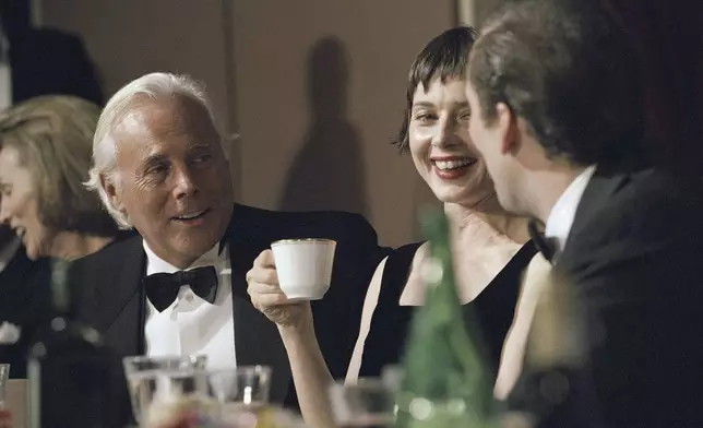 FILE - Fashion designer Giorgio Armani, left, talks with actress Isabella Rossellini and actor Nicolas Cage at a gathering of the National Italian American Foundation in Washington, Oct. 29, 1994. (AP Photo/Greg Gibson, File)