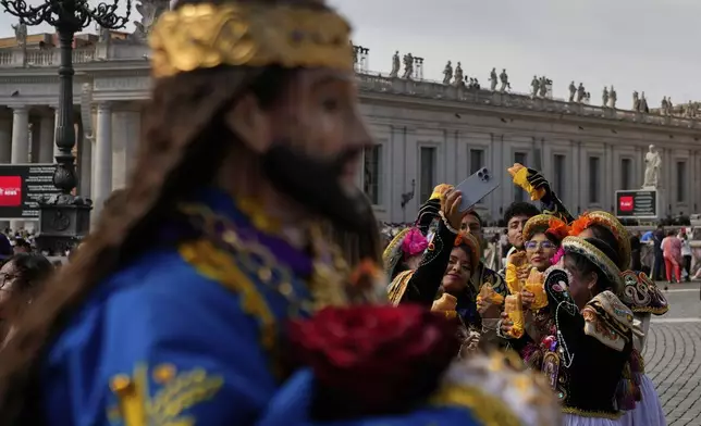 Faithful from Peru take selfie photos near a statue of Jesus Nazareno Cautivo de Monsefu, before Pope Leo XIV appears at his studio's window to bless the faithful gathered in St. Peter's Square at the Vatican for the Angelus prayer, Sunday, Sept. 14, 2025. (AP Photo/Gregorio Borgia)