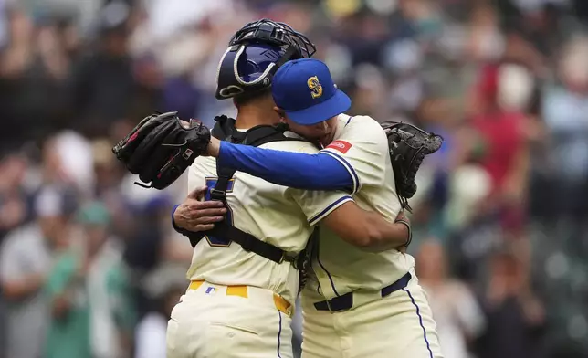 Seattle Mariners' Harry Ford (5) hugs relief pitcher Casey Legumina as they celebrate a win over the Los Angeles Angels in a baseball game Sunday, Sept. 14, 2025, in Seattle. (AP Photo/Lindsey Wasson)