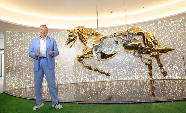 The Hong Kong Jockey Club’s Chief Executive Officer Winfried Engelbrecht-Bresges poses with the “mechanical galloping horse sculpture” by an American artist at the Champions Connection, an impressive sight to draw crowds.