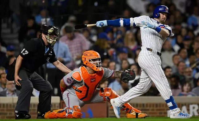 Chicago Cubs' Ian Happ, right, watches his two-RBI double during the third inning of a baseball game against the New York Mets, Wednesday, Sept. 24, 2025, in Chicago. (AP Photo/Paul Beaty)