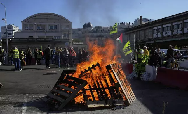 Workers gather next wooden pallets on fire at the Gare de Lyon train station during a protest called by major trade unions to oppose budget cuts, in Paris, France, Thursday, Sept. 18, 2025. (AP Photo/Michel Euler)