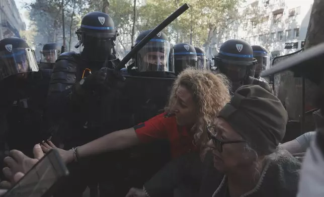 Police officers face protesters during a demonstration called by major trade unions to oppose budget cuts, in Paris, France, Thursday, Sept. 18, 2025. (AP Photo/Thibault Camus)