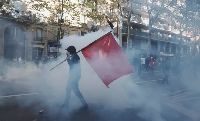 Protesters march in the teargas during a demonstration called by major trade unions to oppose budget cuts, in Paris, France, Thursday, Sept. 18, 2025. (AP Photo/Thibault Camus)