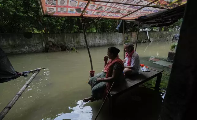A couple drinks tea sitting in front of their inundated house after the river Yamuna, swollen by incessant rain in the higher regions, overran its banks, in New Delhi, India, Friday, Sept. 5, 2025. (AP Photo/Manish Swarup)
