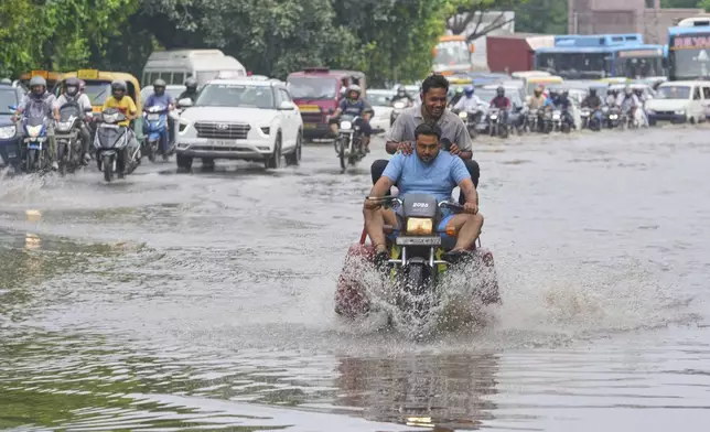 Commuters wade through the flooded water on a road after the river Yamuna, swollen by incessant rain in the higher regions, overran its banks, in New Delhi, India, Friday, Sept. 5, 2025. (AP Photo/Manish Swarup)
