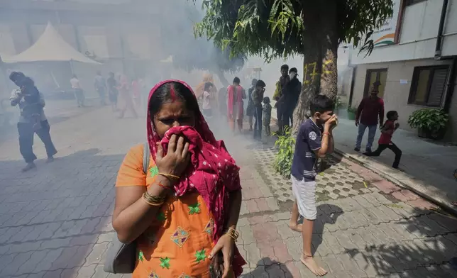 Bindu Pandey, center, cover her nose as officials fumigate in a temporary school shelter, which houses residents displaced from the banks of the Yamuna River by incessant rain in the higher regions in New Delhi, India, Friday, Sept. 5, 2025. (AP Photo/Manish Swarup)