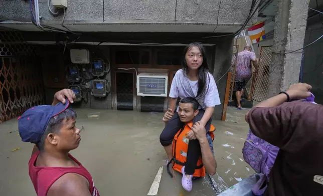 A volunteer lifts a young girl onto his shoulders, carrying her to a safer place after evacuating her and others by boat after the river Yamuna, swollen by incessant rain in the higher regions, overran its banks, in New Delhi, India, Friday, Sept. 5, 2025. (AP Photo/Manish Swarup)