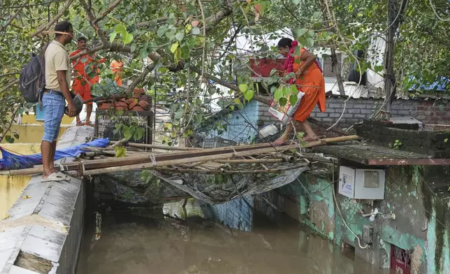Bindu Pandey, 40, right, leaves her flooded house to a temporary shelter in New Delhi, India, Friday, Sept. 5, 2025. (AP Photo/Manish Swarup)