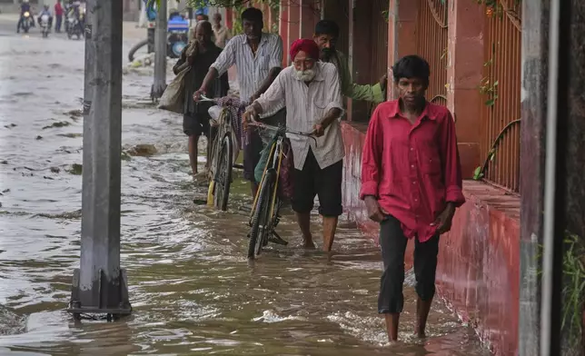 Commuters wade through the flooded water on a road after the river Yamuna, swollen by incessant rain in the higher regions, overran its banks, in New Delhi, India, Friday, Sept. 5, 2025. (AP Photo/Manish Swarup)