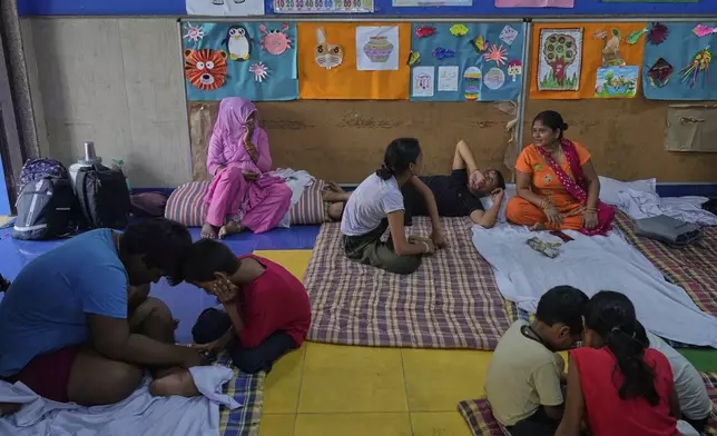 Bindu Pandey, right, talks to her relatives in a temporary school shelter, which houses residents displaced from the banks of the Yamuna River by incessant rain in the higher regions, in New Delhi, India, Friday, Sept. 5, 2025. (AP Photo/Manish Swarup)