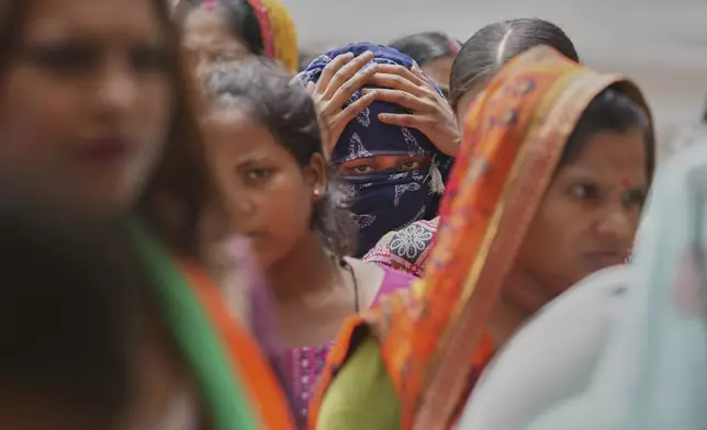 People stand in a queue for food in a temporary school shelter, which houses residents displaced from the banks of the Yamuna River by incessant rain in the higher regions in New Delhi, India, Friday, Sept. 5, 2025. (AP Photo/Manish Swarup)