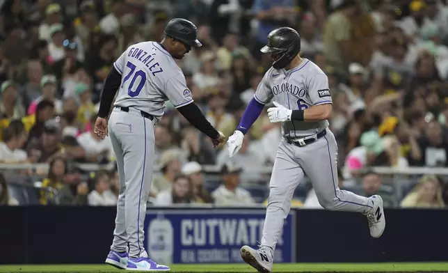 Colorado Rockies' Kyle Farmer, right, celebrates with third base coach Andy González after hitting a home run during the fourth inning of a baseball game against the San Diego Padres Friday, Sept. 12, 2025, in San Diego. (AP Photo/Gregory Bull)