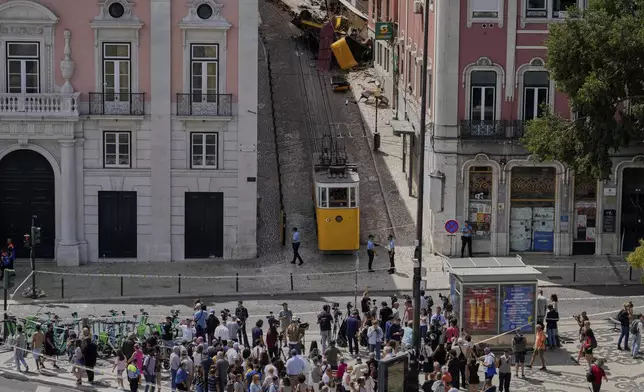People look at a tourist streetcar derailed and crashed in Lisbon, Portugal, Thursday, Sept. 4, 2025. (AP Photo/Armando Franca)