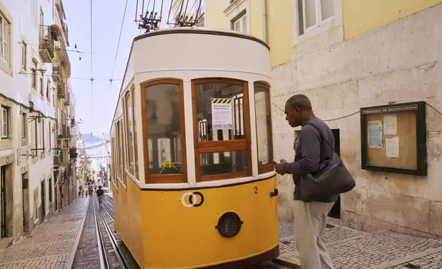 A man reads a sign announcing that the streetcar is out of service in Lisbon, Portugal, Thursday, Sept. 4, 2025. (AP Photo/Ana Brigida)