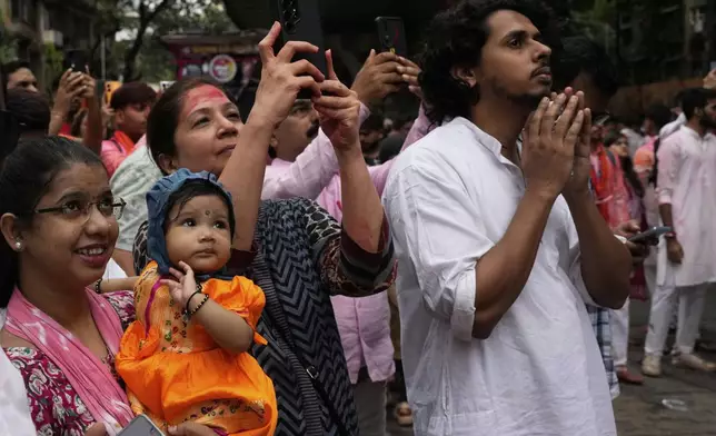 People watch as an idol of elephant-headed Hindu god Ganesha is taken for immersion on the final day of the ten-day long Ganesh Chaturthi festival in Mumbai, India, Saturday, Sept. 6, 2025. (AP Photo/Rajanish Kakade)