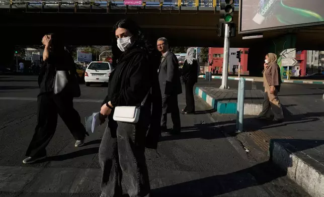 People cross an intersection in northern Tehran, Iran, Sunday, Sept. 28, 2025. (AP Photo/Vahid Salemi)
