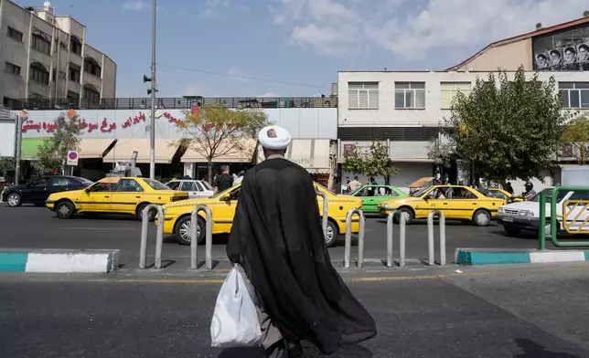 A cleric crosses the Enqelab-e-Eslami (Islamic Revolution) street, in Tehran, Iran, Saturday, Sept. 27, 2025. (AP Photo/Vahid Salemi)