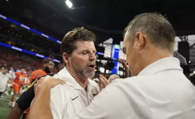 Virginia Tech head coach Brent Pry meets South Carolina head coach Shane Beamer after an NCAA college football game, Sunday, Aug. 31, 2025, in Atlanta. (AP Photo/Brynn Anderson)