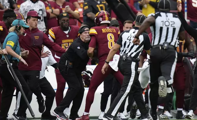 Washington Commanders Dan Quinn is run into on the sideline during the first half of NFL football game against the Las Vegas Raiders, Sunday, Sept. 21, 2025, in Landover, Md. (AP Photo/Stephanie Scarbrough)