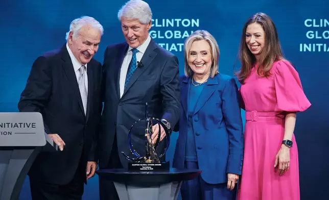 Former U.S. President Bill Clinton, second left, smiles with American businessman Tom Golisano, left, as he awards him with "The Clinton Global Citizen Award" next to former United States Secretary of State Hillary Clinton, second right, and Chelsea Clinton during the Clinton Global Initiative on Wednesday, Sept. 24, 2025, in New York. (AP Photo/Andres Kudacki)