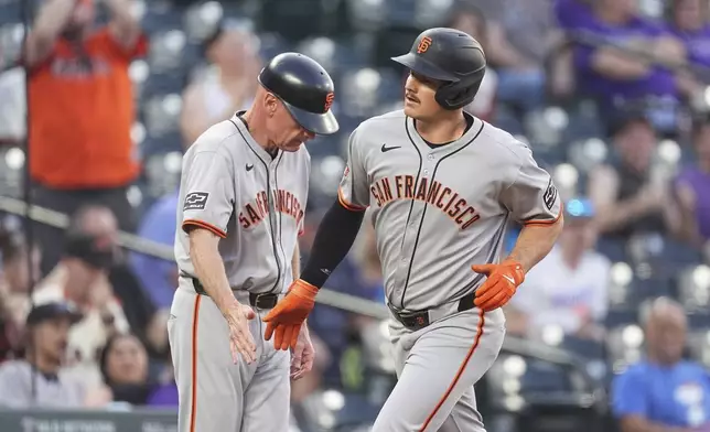 San Francisco Giants third base coach Matt Williams, left, congratulates Matt Chapman, as he circles the bases after hitting a solo home run off Colorado Rockies starting pitcher Germán Márquez in the second inning of a baseball game Wednesday, Sept. 3, 2025, in Denver. (AP Photo/David Zalubowski)