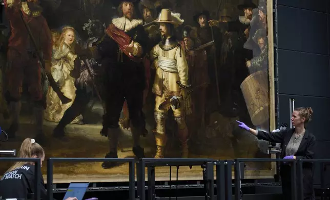 An art restorer points at the image of a dog in Rembrandt's Night Watch at Amsterdam's Rijksmuseum, Netherlands, Tuesday, Sept. 23, 2025. (AP Photo/Peter Dejong)