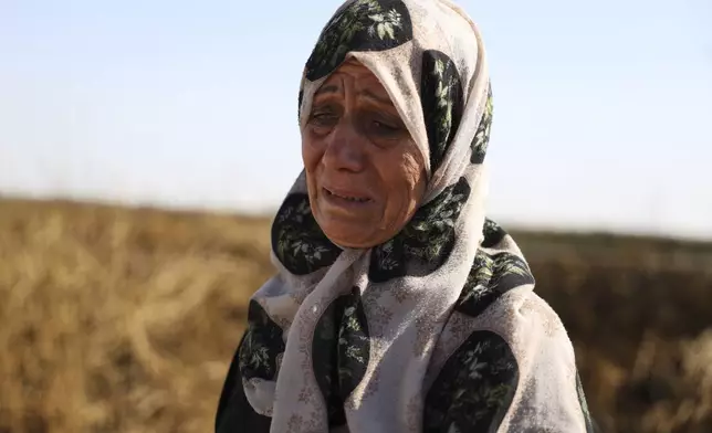 Samira Alloush, searching for her missing son, cries as she watches the Syrian Civil Defense workers inspect clothes found alongside human remains in Otaiba, on the outskirts of Damascus, Syria, Friday, Sept. 19, 2025. (AP Photo/Omar Albam)