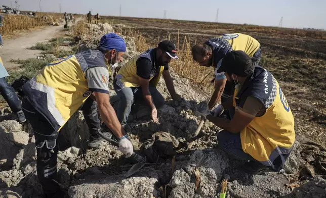 Syrian Civil Defense workers collect human remains found in Otaiba, on the outskirts of Damascus, Syria, Friday, Sept. 19, 2025. (AP Photo/Omar Albam)