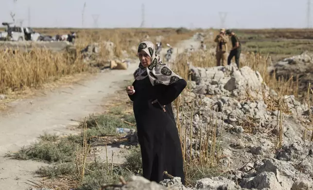 Samira Alloush, searching for her missing son, cries as she watches the Syrian Civil Defense workers inspect clothes found alongside human remains in Otaiba, on the outskirts of Damascus, Syria, Friday, Sept. 19, 2025. (AP Photo/Omar Albam)