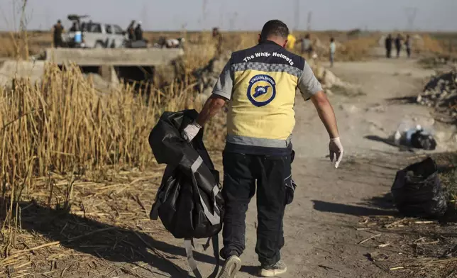 A Syrian Civil Defense worker carries a plastic bag containing human remains found in Otaiba, on the outskirts of Damascus, Syria, Friday, Sept. 19, 2025. (AP Photo/Omar Albam)