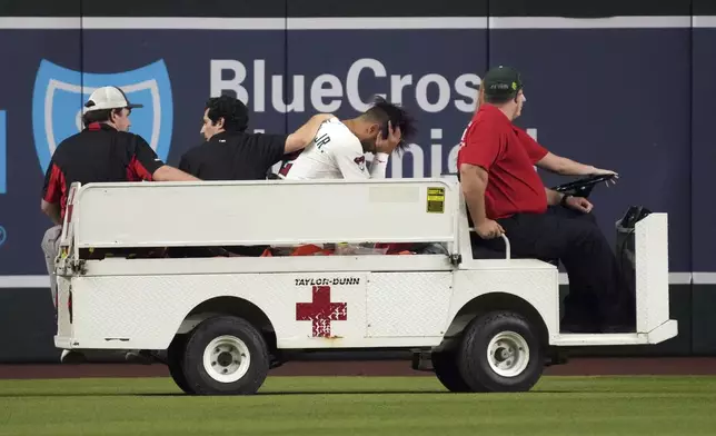 Arizona Diamondbacks' Lourdes Gurriel Jr., third from left, is taken out on a cart after diving for a ball hit by Texas Rangers' Rowdy Tellez in the sixth inning of a baseball game, Monday, Sept. 1, 2025, in Phoenix. (AP Photo/Rick Scuteri)