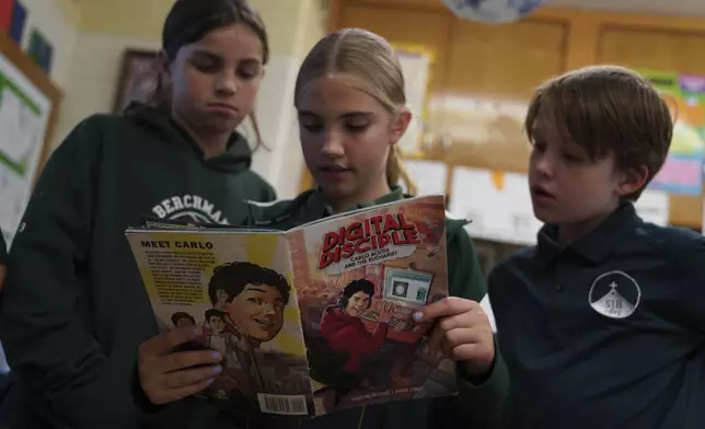 Fifth grade students, Paulie Alfirevich, left, Paige Lange, center, and Alex Miller, read a comic book about the life of Blessed Carlo Acutis, who will be canonized a saint by Pope Leo XIV, entitled "Digital Disciple" during a class activity at St. John Berchmans' school on Wednesday, Sept. 3, 2025, in Chicago. (AP Photo/Jessie Wardarski)