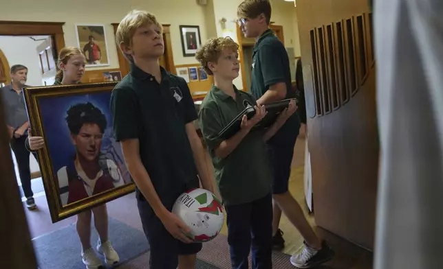 Students of St. John Berchmans' school hold items often linked to Blessed Carlo Acutis, who will be canonized a saint by Pope Leo XIV, before Mass at Blessed Carlo Acutis Parish, on Wednesday, Sept. 3, 2025, in Chicago. (AP Photo/Jessie Wardarski)