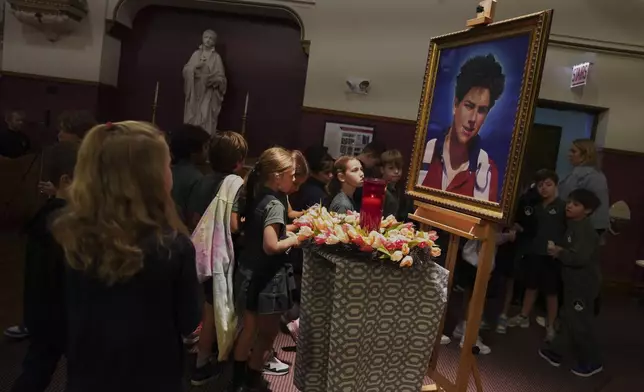 Students of St. John Berchmans' school walk past a photo of Blessed Carlo Acutis, who will be canonized a saint by Pope Leo XIV, after Mass at Blessed Carlo Acutis Parish, on Wednesday, Sept. 3, 2025, in Chicago. (AP Photo/Jessie Wardarski)