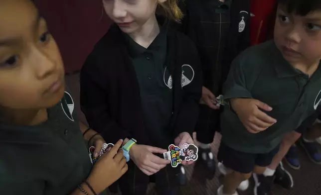 St. John Berchmans' school students hold stickers of Blessed Carlo Acutis, who will be canonized a saint by Pope Leo XIV, after Mass at Blessed Carlo Acutis Parish, on Wednesday, Sept. 3, 2025, in Chicago. (AP Photo/Jessie Wardarski)