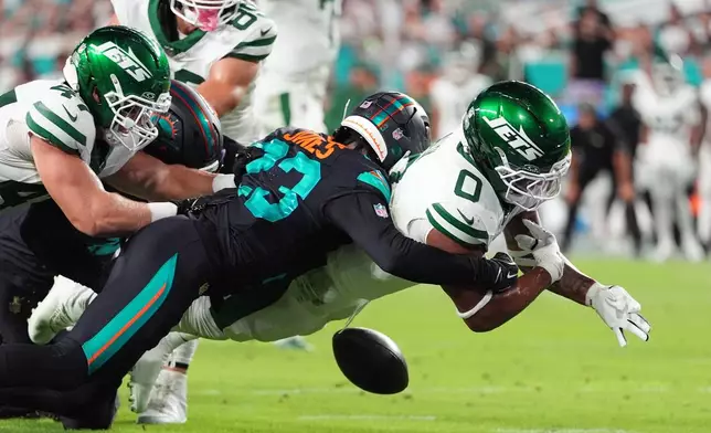 New York Jets running back Braelon Allen (0) fumbles the ball after taking a hit from Miami Dolphins cornerback Jack Jones, rear, in the first half of an NFL football game, Monday, Sept. 29, 2025, in Miami Gardens, Fla. (AP Photo/Rebecca Blackwell)